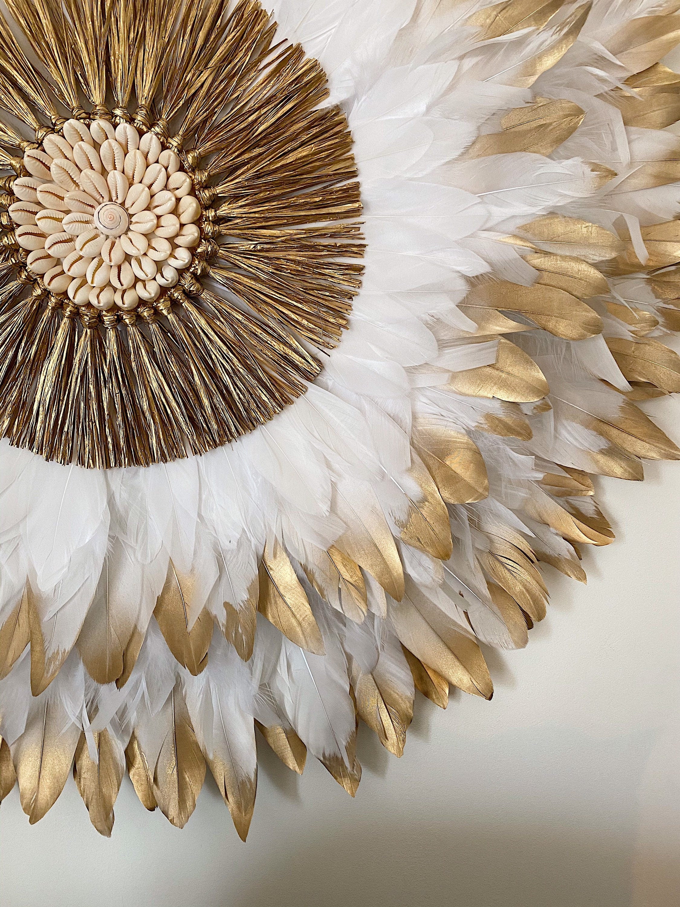 JUJUHAT « PRÉCIEUX DORÉ » avec ses plumes blanches et dorées et son cœur en raphia doré et coquillages cauris