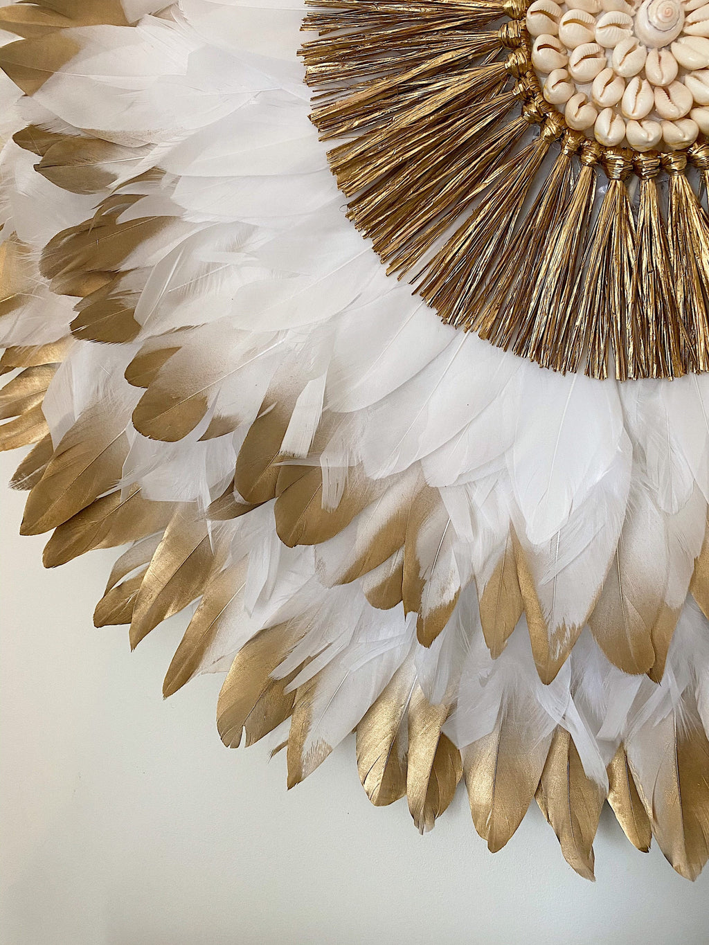 JUJUHAT « PRÉCIEUX DORÉ » avec ses plumes blanches et dorées et son cœur en raphia doré et coquillages cauris
