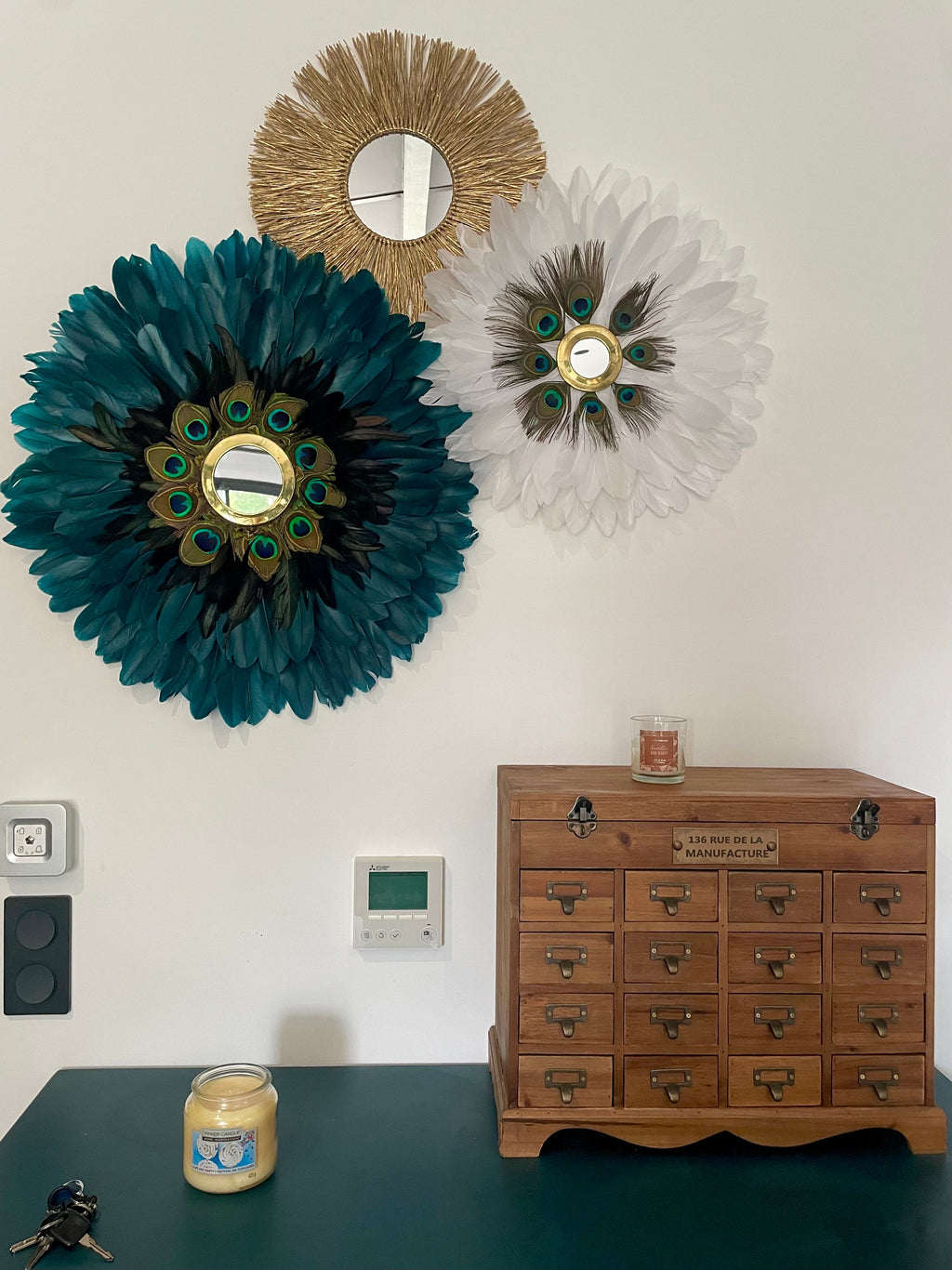 Trio mural Juju Hats “GEORGIOS” – Déco murale bohème chic – Plumes bleu paon, blanc et noir – Miroir soleil en raphia doré – Fait main