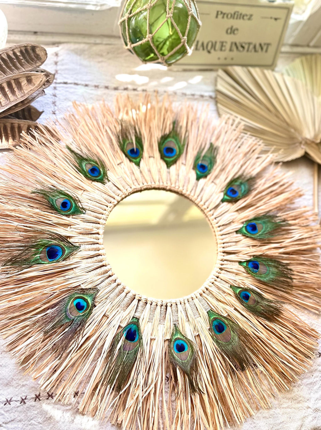 Miroir mural GAÏA – miroir en raphia et plumes de paon 58 cm – décoration murale bohème chic et naturelle fait main